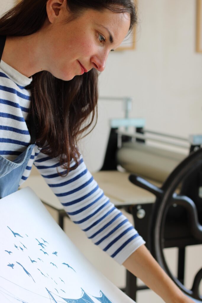 Noémie Courant imprime une linogravure à la main avec sa presse dans son atelier